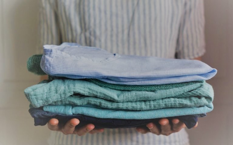 woman holding a stack of handmade clothes