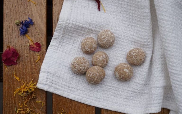 diy aroma stones on a white kitchen towel on a wooden table next to some colourful dried flowers