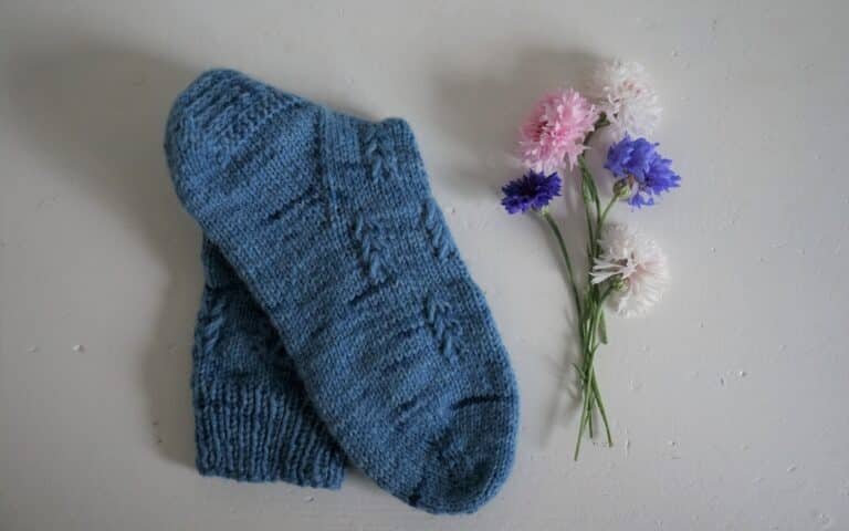 a blue hand knitted song a some flowers next to it