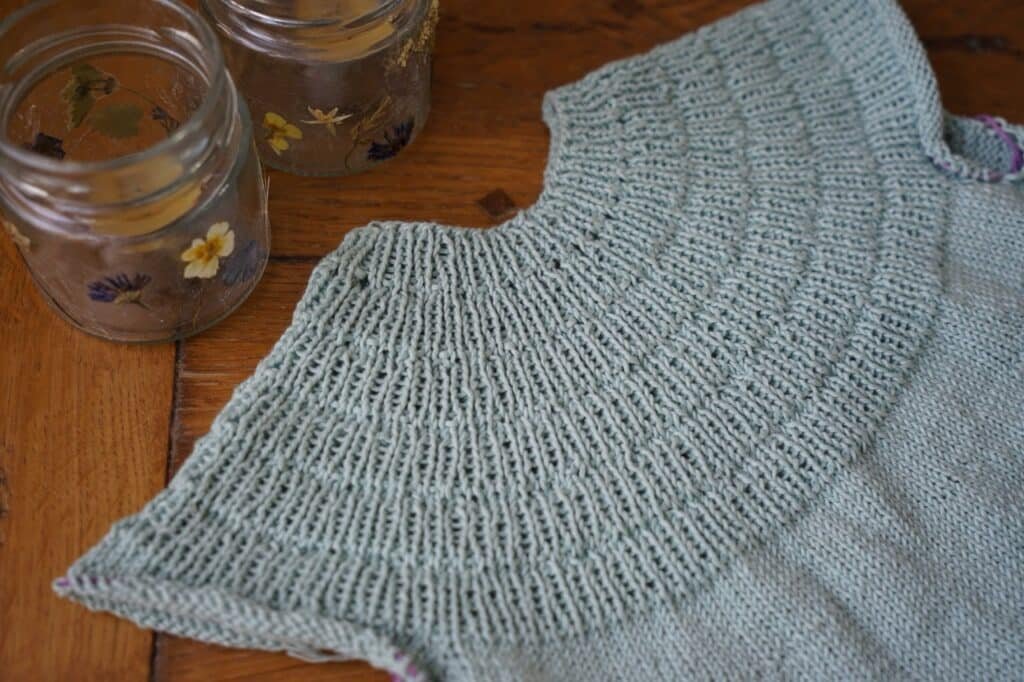 anker dress in progress, laying on a table next to two floral candle holders