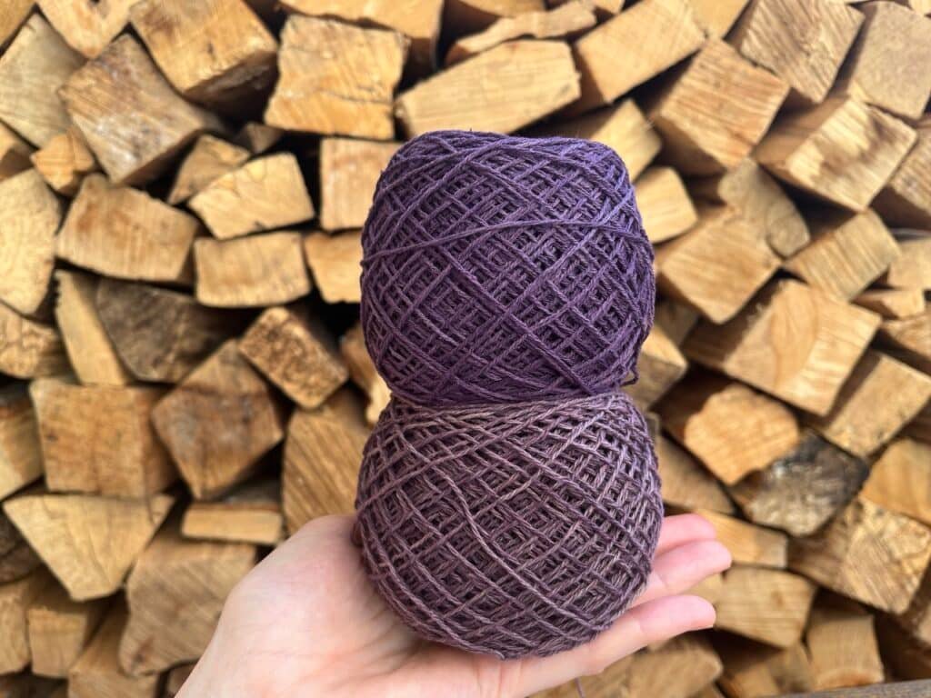 holding two purple cakes that I dyed with logwood in front of firewood