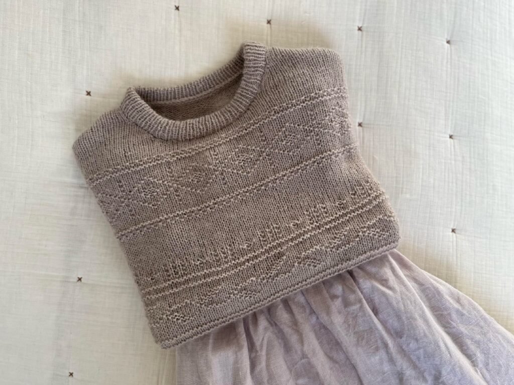 my hand knitted porcelain damask sweater and a dress laying on the bed