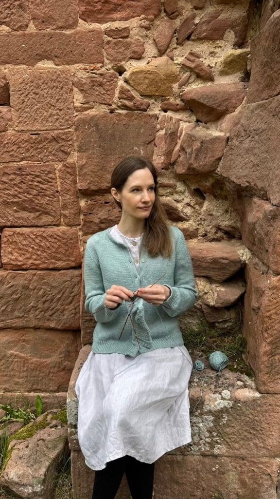 wearing my hand knitted oxford cardigan, sitting in front of a castle and knitting