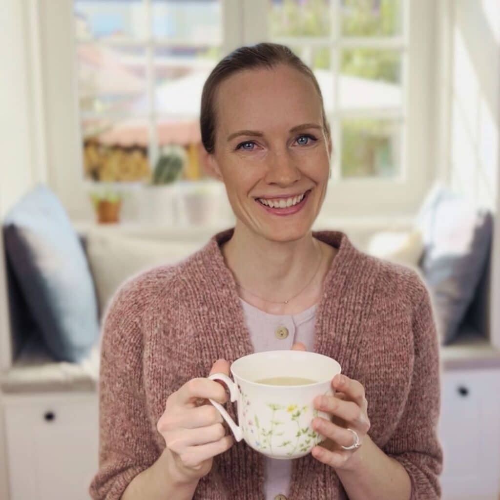wearing my hand knitted timepiece cardigan, holding a cup of tea