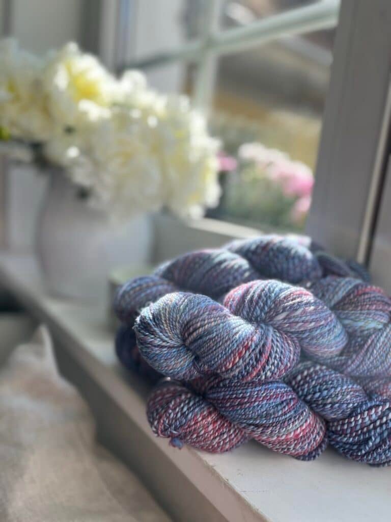 four skeins of colorful handspun yarn on a window sill